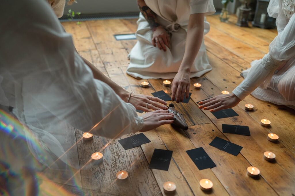 People Sitting on the Wooden Flooring while Putting their Hands Above the Wooden Figurine